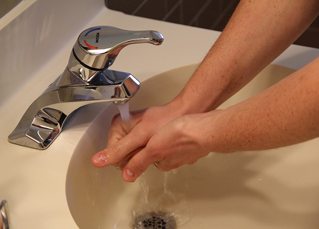 Zdjęcie przedstawia mycie rąk w umywalce.